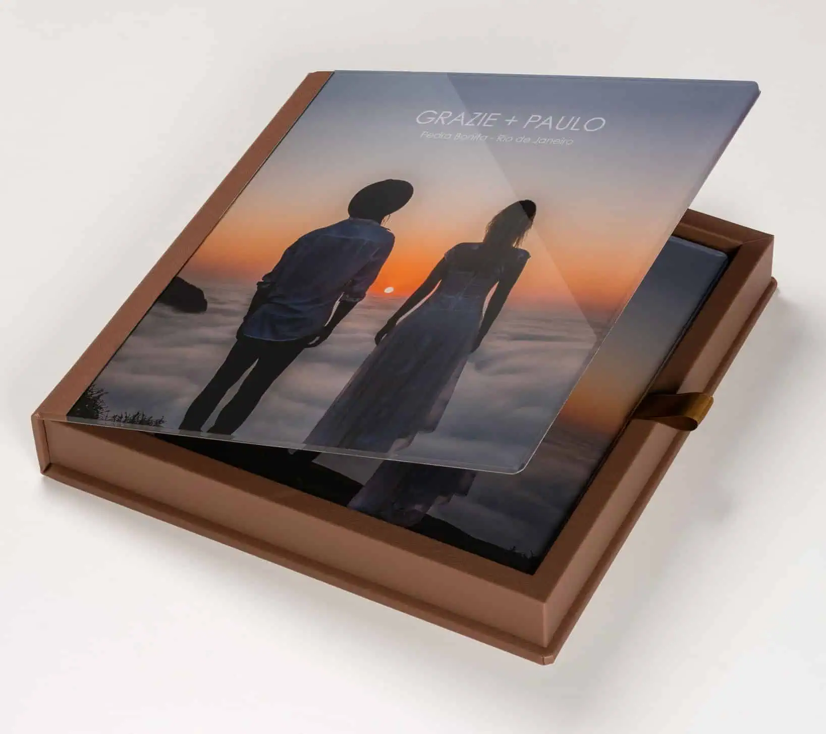 Alto texto: Álbum de fotos com capa de vidro oceano ao pôr do sol, casal em momento romântico, presente especial.
