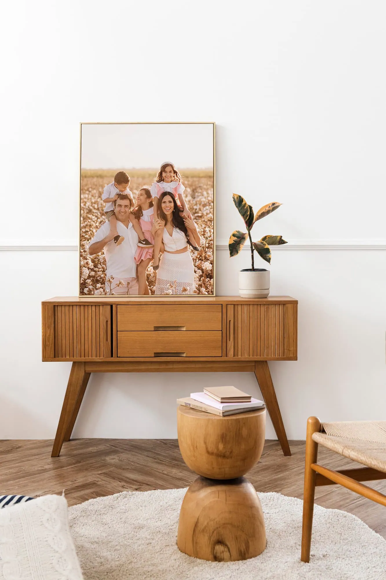 Família sorridente em foto decorativa de sala com mobiliário de madeira e planta decorativa.