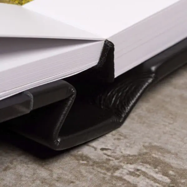 1. Livro aberto com capa de couro preto e marca-página de feltro preto.