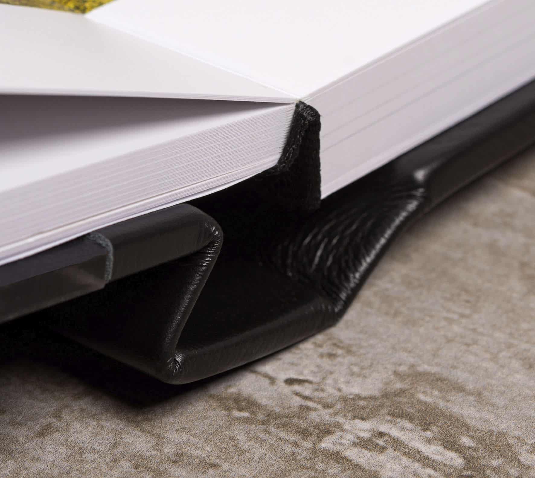 1. Livro aberto com capa de couro preto e marca-página de feltro preto.