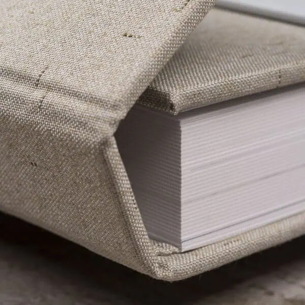 Foto Imã 1. Livro com capa de tecido cru e páginas brancas, estilo artesanal, para decoração ou leitura.