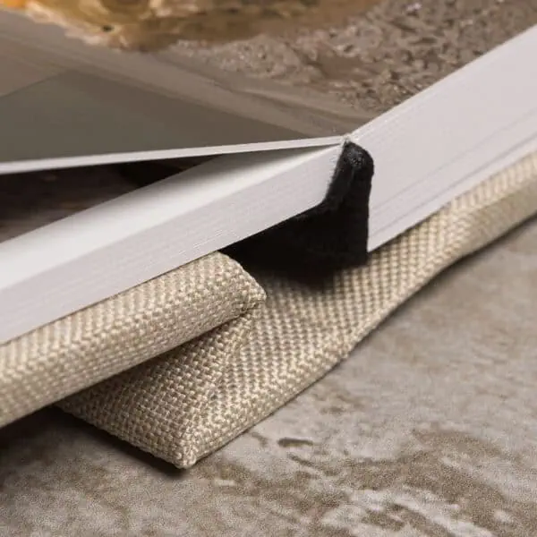 Livro de amostras de cores com capa de tecido e páginas brancas, em ambiente interno.