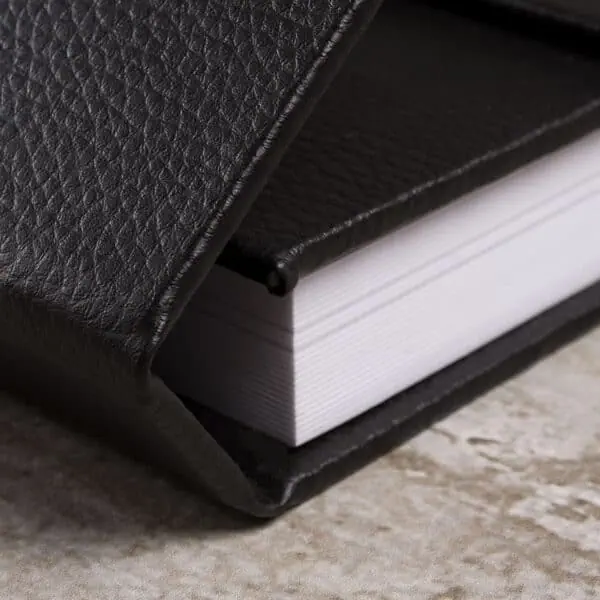 Janela com imã Caderno de couro preto com páginas brancas, ideal para escrita e organização.