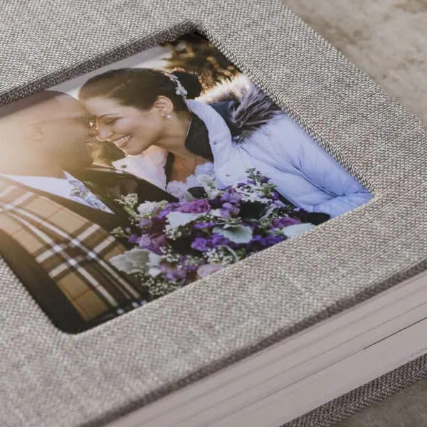 Casal sorridente em livro de fotos de casamento, lembrança de momento especial.