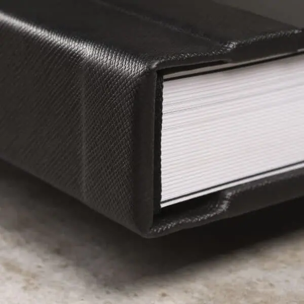 Notebook com capa de couro preta e páginas brancas, ideal para organização e estudos.