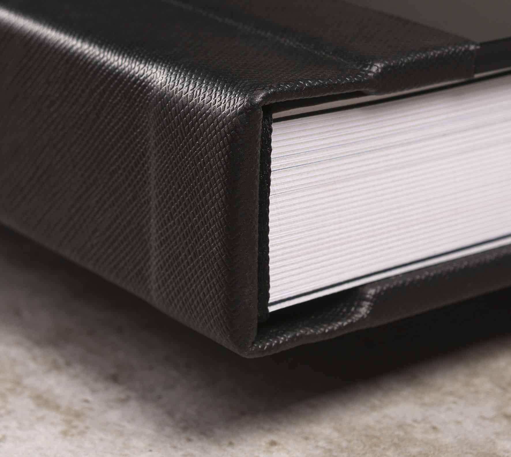 Notebook com capa de couro preta e páginas brancas, ideal para organização e estudos.