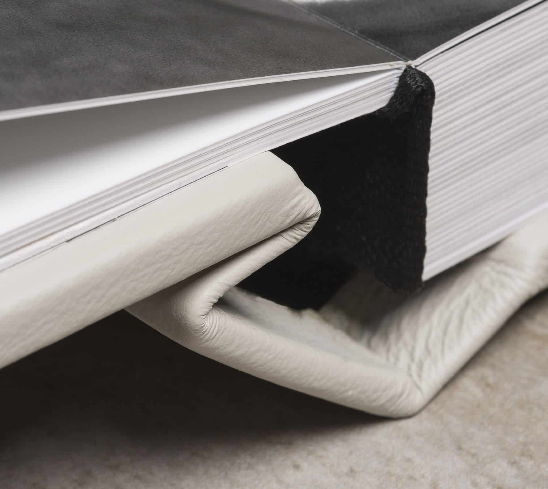 Caderno de capa dura com páginas brancas, ideal para fotografia e arte.