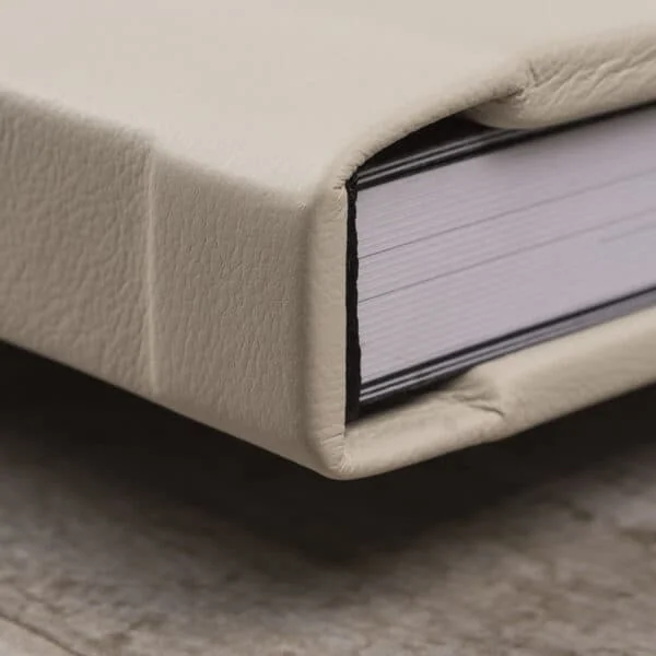 Capa de couro sintético em tom bege cobrindo um álbum fotográfico artesanal com detalhes em relevo.