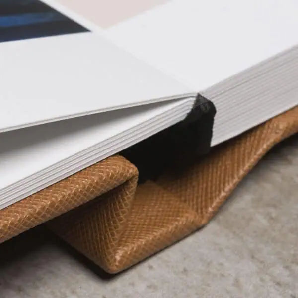 Livro de fotografia aberto sobre mesa, destaque para detalhes e acabamento.
