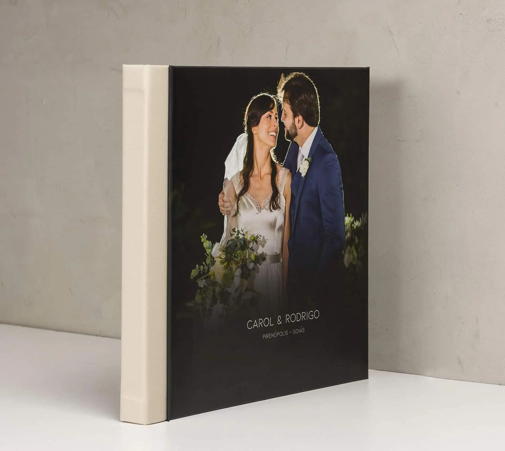 Casamento em livro fotográfico personalizado com casal sorridente ao lado.