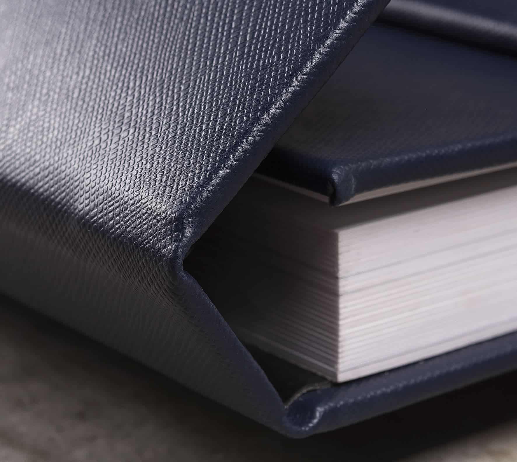 Caderno de couro azul escuro com páginas brancas, estilo profissional e elegante.