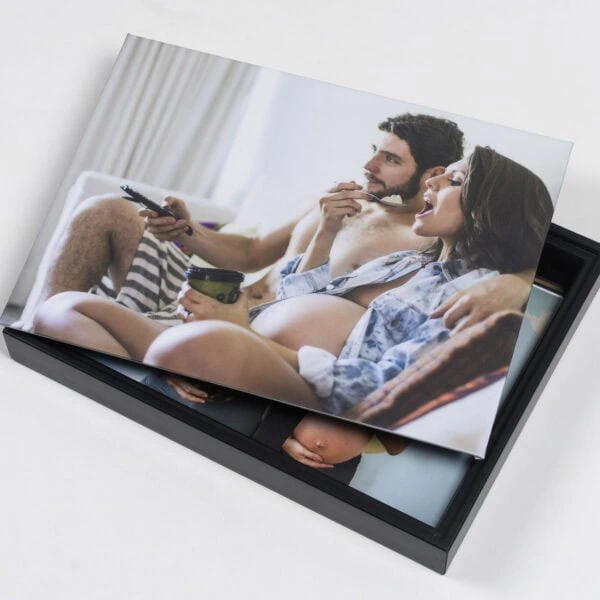 Box para Foto 6 Casal grávida apreciando fotos impressas em álbum fotográfico personalizado.