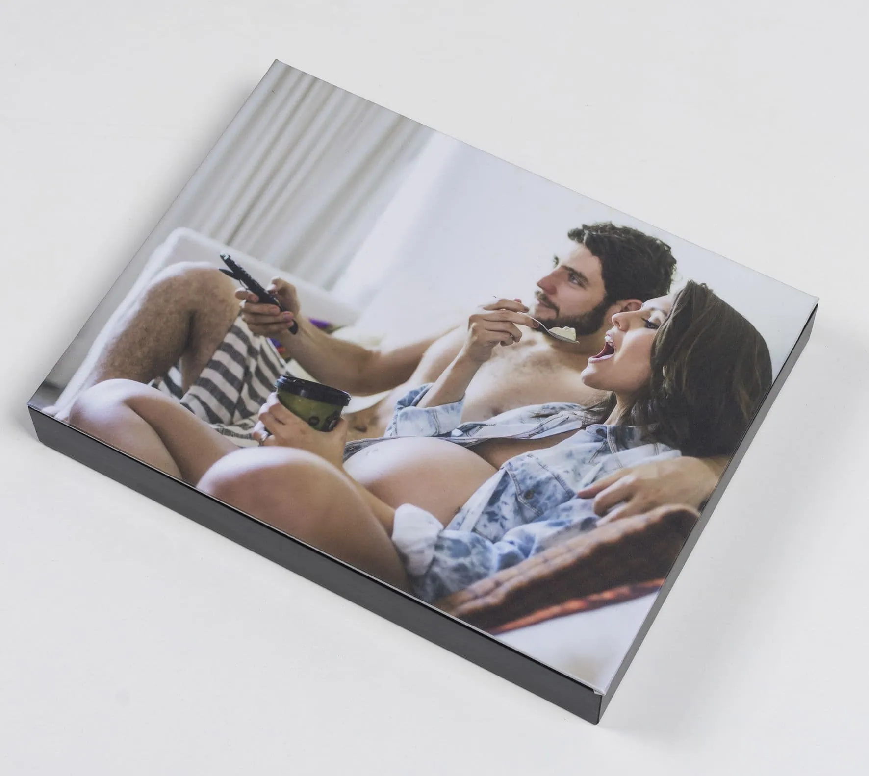 Casal fazendo sessão de fotos em cama com fotos do Fotoclub.