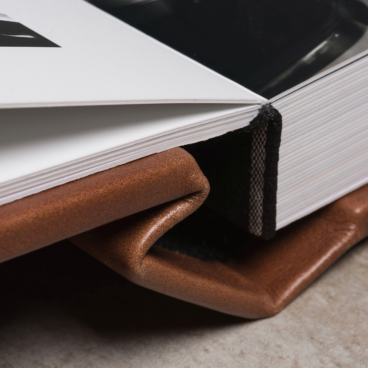 Álbum de fotos com capa de couro e páginas brancas, foco na textura e detalhes do material.