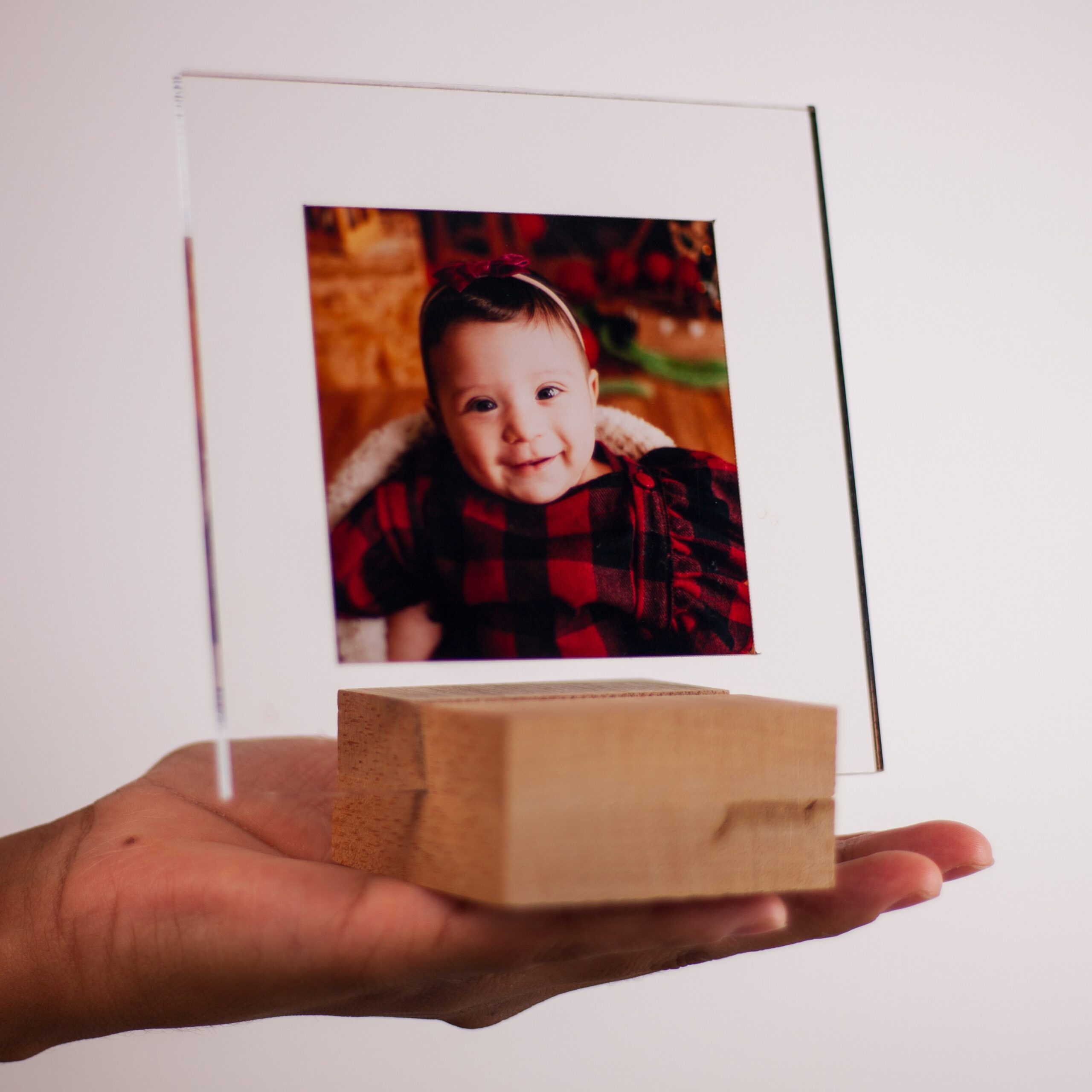 Criança sorridente em quadro de vidro com foto de família, exibindo talento em fotografia de retrato.