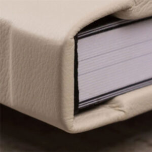 Capa de livro de couro branco com páginas visíveis.
